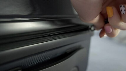 Close up hand of Young Asian travel woman unpacking suitcase by unzipping luggage on bed.