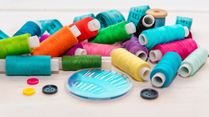 On the table is a large number of threads, along with needles and a ruler.