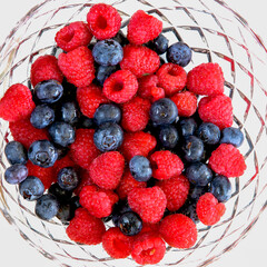 Blueberries and raspberries in a glass bowl.
