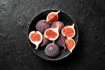 Fresh whole and sliced fig on black background, top view