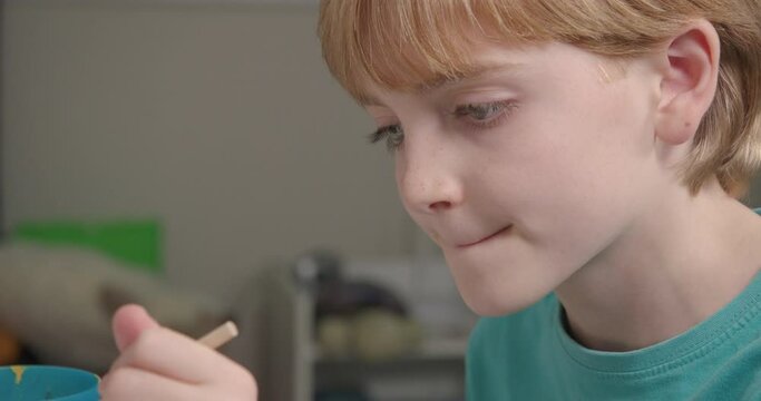 Close-up, a 9 year old boy paints a money box, London, UK