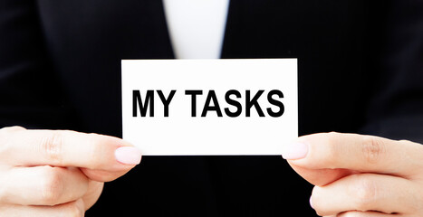 The businessman holds a business card with the inscription MY TASKS.