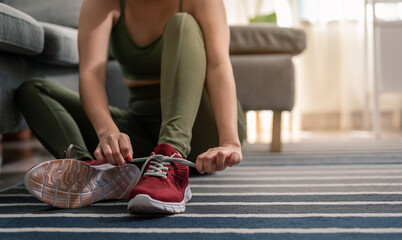 A woman is wearing shoes to exercise in her home. Exercise indoors during quarantine. Exercise, home activities