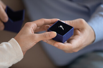 Will you marry me. Close up of young male hand holding gift box with engagement ring presenting it...
