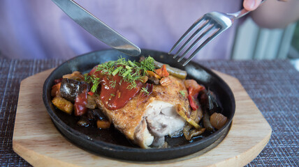 Fried chicken with vegetables. The lunch process. The knife cuts the dish.