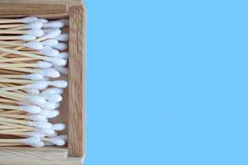 Closeup view on bamboo cotton swabs in wooden box on blue background with copyspace. Zero waste and sustainable lifestyle concept. Eco friendly bathroom essentials