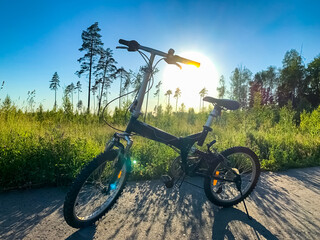 Bright beautiful scenery with a bike near the field as the sun rises at the horizon. Bicycle mood in nature with meadow