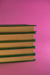 stack of old books lies on a pink background.