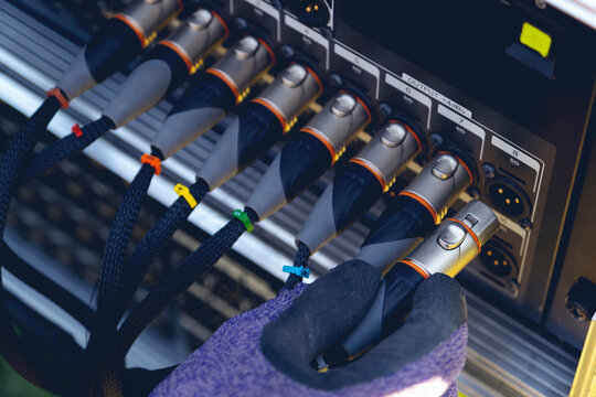 Sound engineer plugging audio cable on studio system boxes.