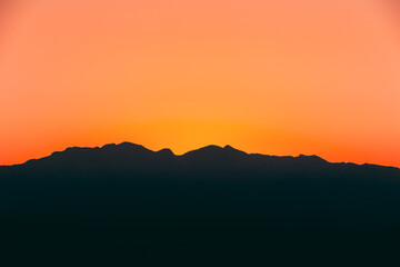 Obraz premium Dark Silhouette of Mountains on Yellow Sunset Sky Background