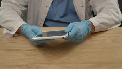 Prevention of COVID-19. A man in a protective medical suit wipes a tablet with an antibacterial disinfectant wipe to destroy the coronavirus on surfaces and work safely. Close up. Slow motion - Powered by Adobe