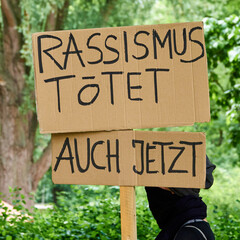 Demonstration against racism with a poster with the German inscription: Racism kills. Even now.