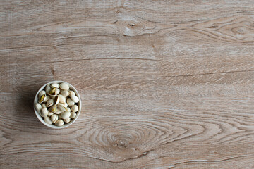nuts in a cup on an old wood grain table Left corner and take a closeup and top view, has copyspace for text input, the photo is a landscape