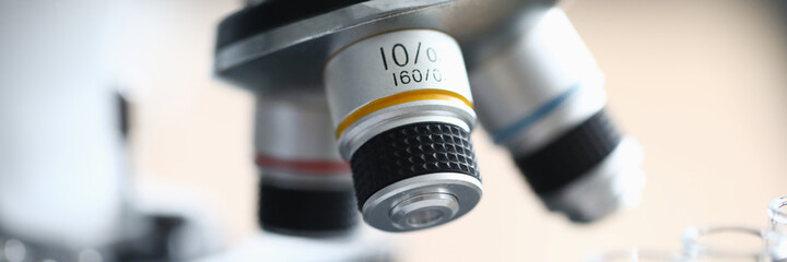 Close-up of modern microscope standing in laboratory. Glass flasks with liquid. Macro shot of device to examine sample in lab. Investigation and research material concept © H_Ko