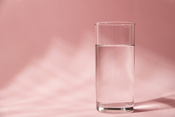 Glass of water on a pink background