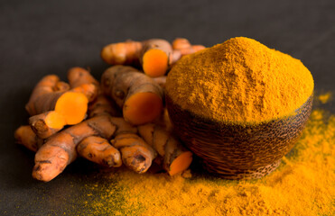Turmeric (curcumin) powder and fresh rhizome on a black background,For spices.