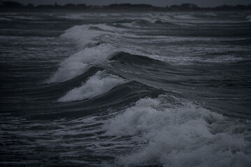 Intentionally dark image of rough seas with waves crushing on the beach during high tide and...