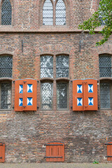 Fototapeta na wymiar Historic Dutch castle wall with windows with stained glass and multicolored wooden shutters