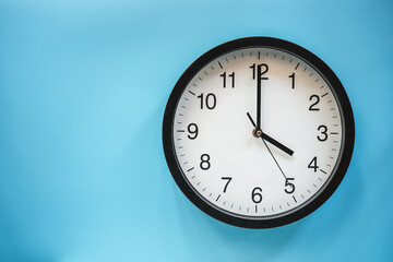 Classic black and white analog clock on blue background at Four o'clock with copy space