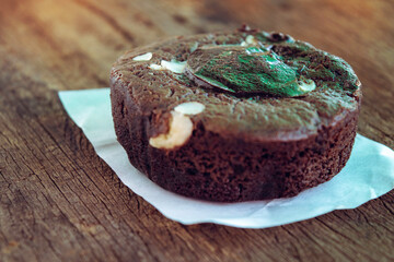 The soft focus silhouette of the black soft-faced brownie cake is so appetizing, laid out on white paper on an old wooden floor.