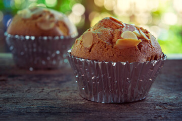 silhouette, brown banana soft cake topped with brown almonds in silver paper Put on the old wooden floor Looks very appetizing With colored bokeh background