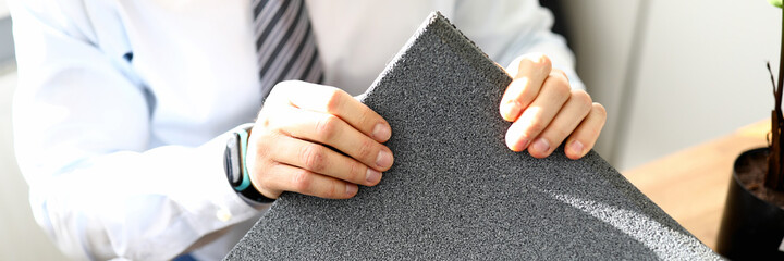 Obraz na płótnie Canvas Close-up of business male holding grey material for apartment renovation. Interior designer office. Construction house. Successful agency and talented architect concept