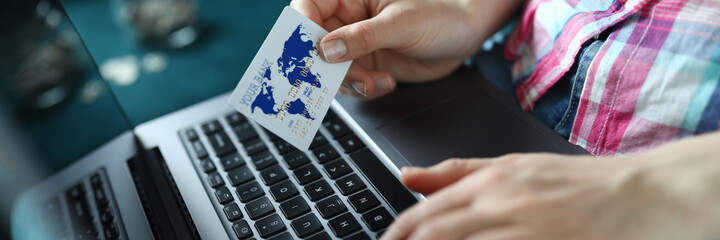 Close-up of person holding plastic credit card and typing on modern computer. Remote payment. Female customer order stuff. Online shopping and technology concept