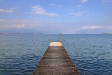 The view along a wooden pier on the banks of Lake Garda in North East Italy.