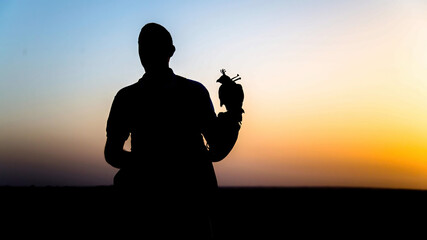 Falcon trainer silhouette in desert with sunset scenery, Dubai, UAE