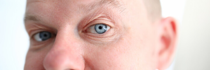 Obraz premium Close-up of middle-aged male posing on camera indoors. Person with mustache. Adult with attractive blue eyes. Funny man with wrinkles. Model and beauty concept