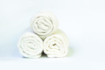 Obraz na płótnie Canvas Stack of bath white rolled towels on light background