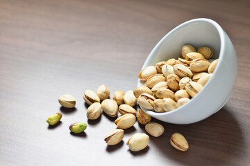 Close-up Pistachio nuts with white bowl on wooden background