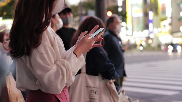 夜の渋谷でスマホを操作する若い女性の手元