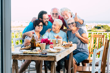 Group of caucasian family people enjoy and celebrate together in outdoor at home with country side green nature view in backgorund - senior and young friends enjoying with food and drinks