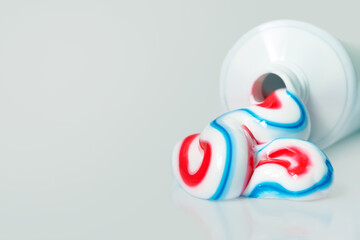 White tube with toothpaste isolated on light background. Tricolor toothpaste, copy space