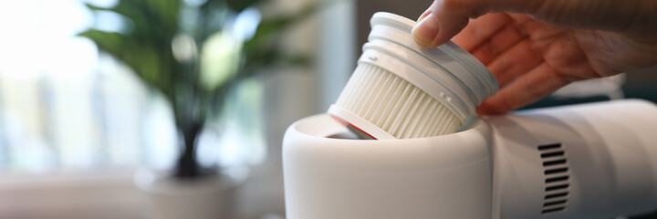 Close-up of persons hand pull out filter of modern white vacuum cleaner to change. Renovation and housewife. Interior design. Technology and cleanliness concept
