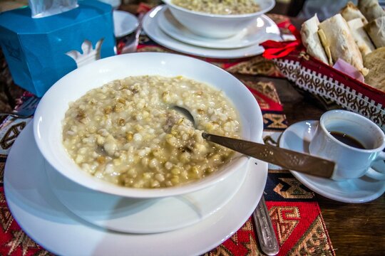 Closeup of traditional Armenian dish harisa - oatmeal with meat. Breakfast in the cafe: porridge, coffee and bread on the table.