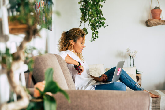 Home lifestyle real scene with people and technology .- beautiful woman sit down on the sofa and use laptop computer and connection for work or look for the web - female caucasian and smart working