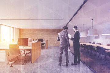 Two businessmen talking in white and wooden open space office