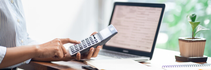 Concept of accounting work, business man doing paperwork using a calculator at the office and Financial data analyzing counting on laptop computer
