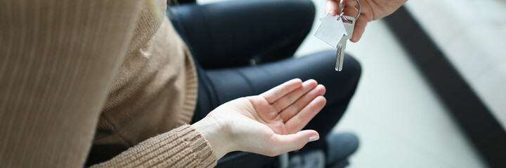 Top view of male businessman giving keys from new house to disabled woman. Female sitting in wheelchair. Moving day into apartment. Handicapped and real estate concept