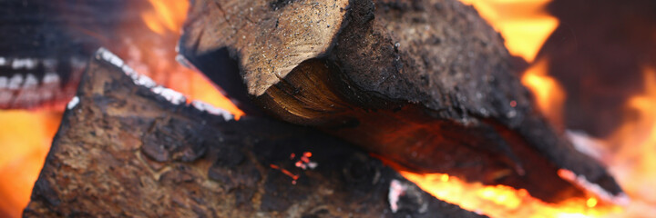 Close-up of actively smoldering embers outside. Red live coals in burning fire. Bonfire on street. Flame and sparks rise up in air. Outdoors activity and barbecue concept