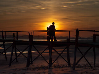 Fototapeta na wymiar young man silhouette at sunset on the old pier