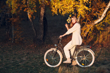 Fototapeta premium Happy active young woman riding bicycle in autumn park