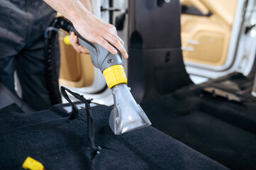 Worker cleans car interior with vacuum cleaner