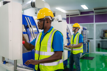 Two mechanical technician operative entering data in cnc milling cutting machine at factory at tool workshop in metal machining industry.
