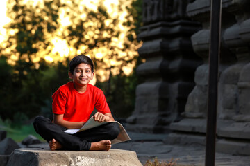 Obraz premium Indian / Asian school boy with note book and studying at home