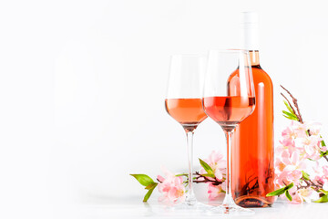 Rose wine glass with bottle on the white table and pink flowers. Rosado, rosato or blush wine tasting in wineshop, bar concept. Copy Space