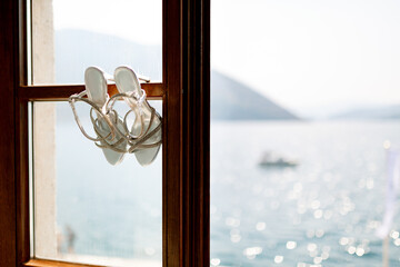 Bridal sandals on a wooden window frame overlooking the sea.