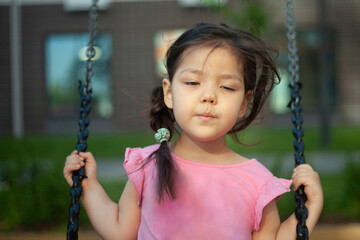 The girl is swinging on a swing. Play on the playground.